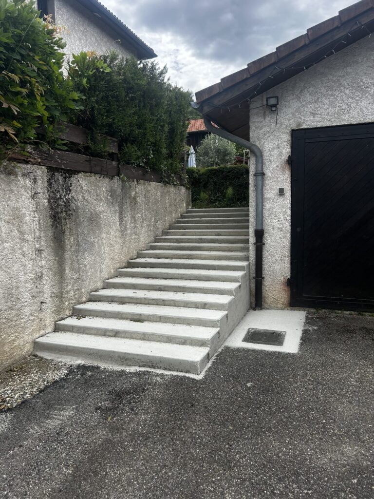 Escalier en béton à marches basses entre deux murs, au Versoud