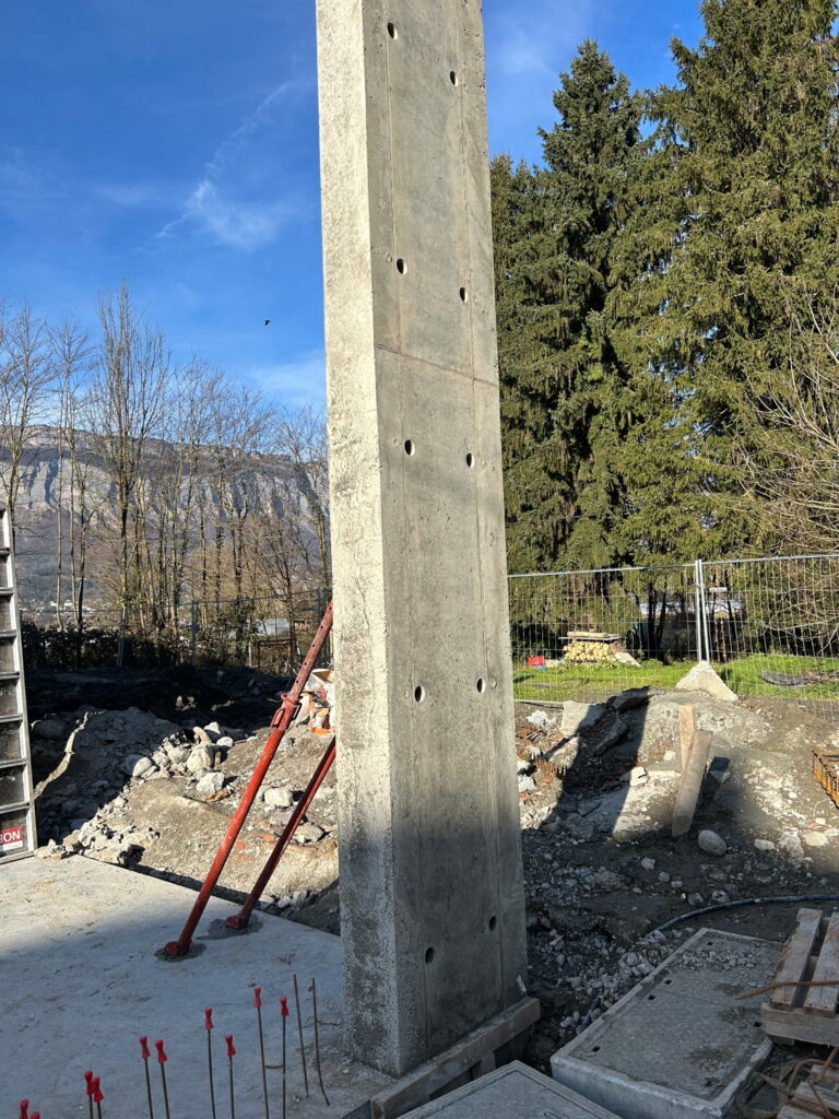 Poteau en béton armé décoffré le long du mur en pierre